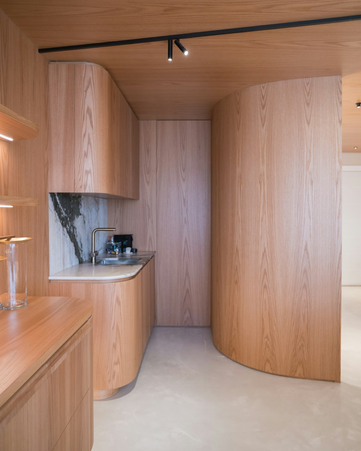 Curved oak joinery and stone benchtop inside a Deol Built residence